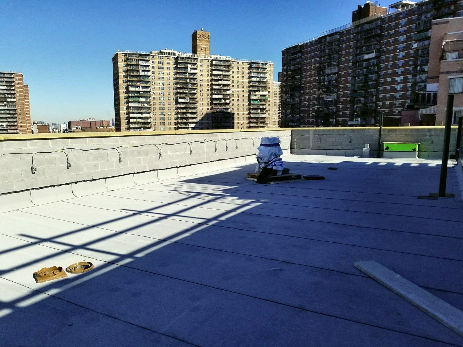 Finished white reflective flat roof by our crew with city buildings behind